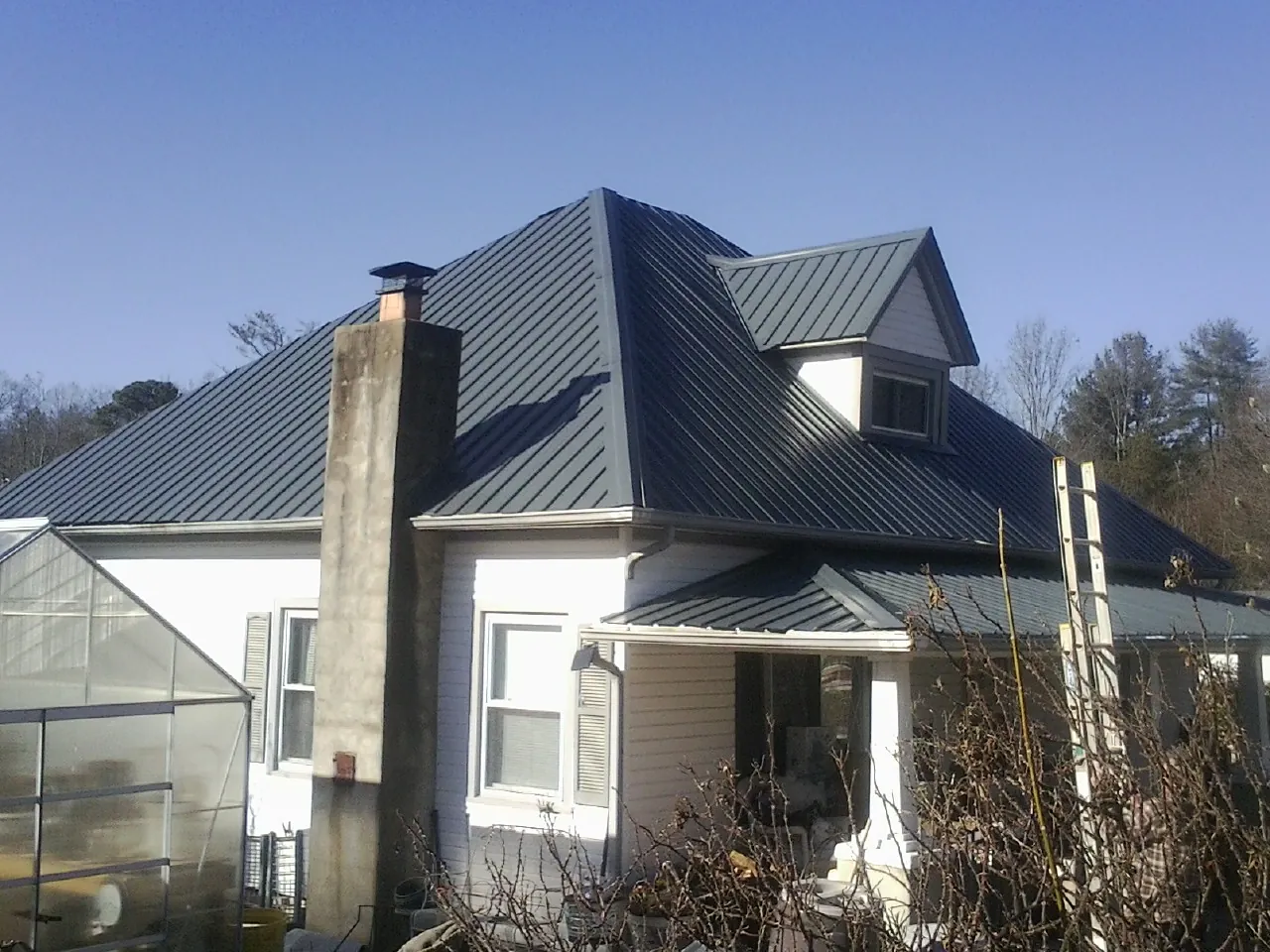 Dark blue standing seam metal roof on a white farmhouse with dormer — Slate & Tile Roof Repair by Roofing Brothers in Unicoi