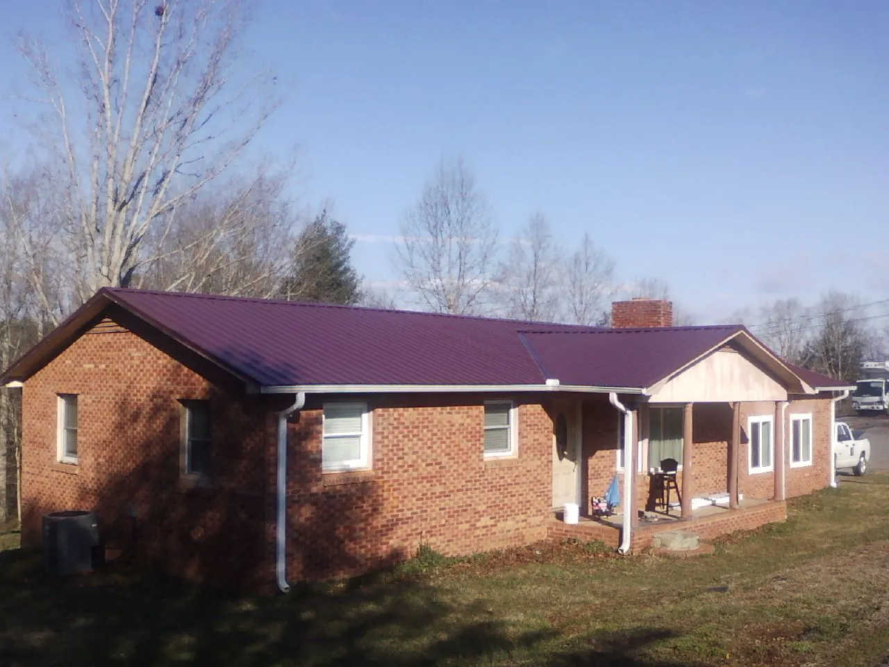 Burgundy metal roof on a brick ranch home with a new addition in Unicoi