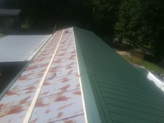 Old rusted panels beside newly installed green metal roofing — Wind Damage Roof Repair by Roofing Brothers in Unicoi