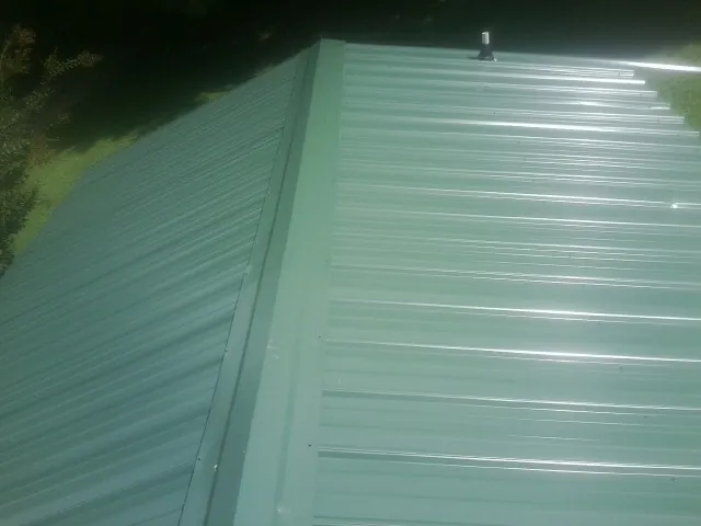 New green metal panels meeting at the ridge of a roof — Flat Roof Repair work by our crew in Unicoi