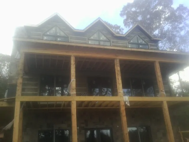 Dormers and porch framing on a large log home under construction — Roof Coating work by our crew in Unicoi