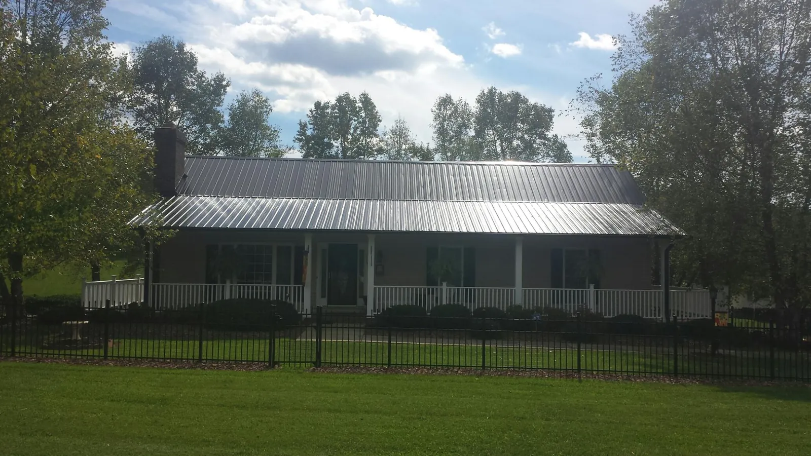 Gray metal roof on a brick ranch with a full width front porch — Gutter Guard Installation work by our crew in Unicoi