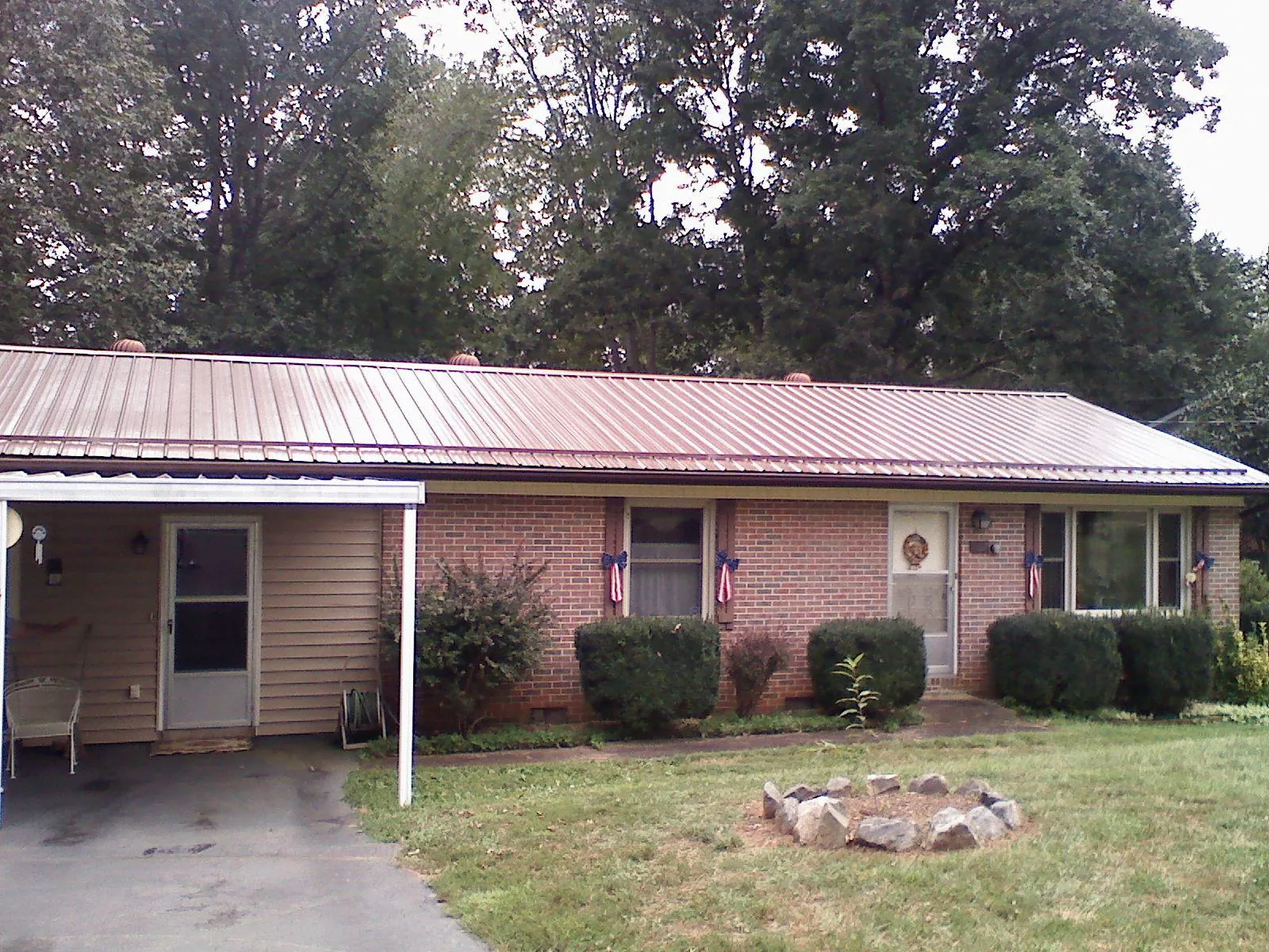 Bronze metal roof and carport on a brick ranch home — Roof Repair work by our crew in Unicoi