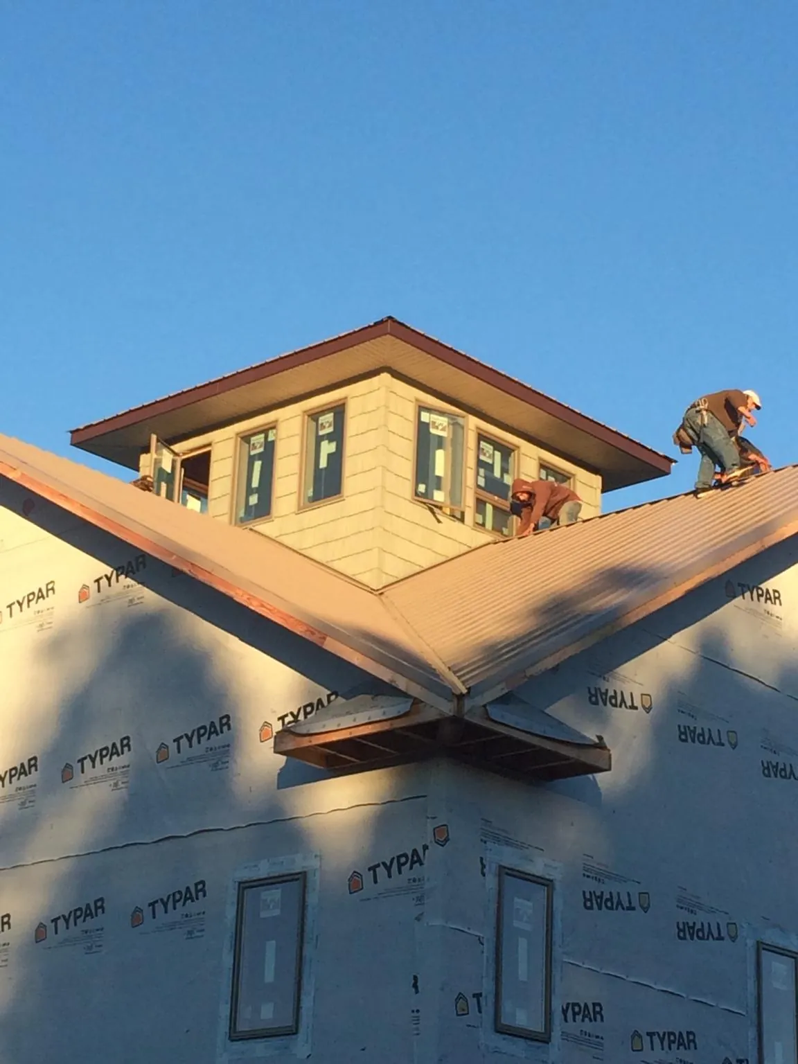 Roofers working around a rooftop cupola on a new metal roof at sunset — Roof Waterproofing in Unicoi by Roofing Brothers